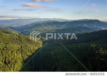 Aerial view of winding road in high mountain pass trough dense green pine woods. Aerial view of winding road in high mountain pass trough dense green pine woods. 92052418