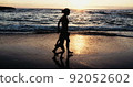 Slow motion of Mother and young girl running on the beach during sunset 92052602
