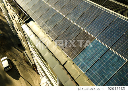 Aerial view of solar photovoltaic panels on a roof top of residential building block for producing clean electric energy. Autonomous housing concept. Aerial view of solar photovoltaic panels on a roof top of residential building block for producing clean electric energy. Autonomous housing concept. 92052685