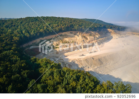 Aerial view of open pit mining site of limestone materials extraction for construction industry with excavators and dump trucks. Aerial view of open pit mining site of limestone materials extraction for construction industry with excavators and dump trucks. 92052696
