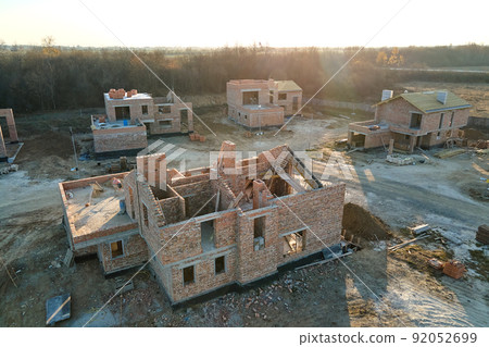 Aerial view of new homes with brick framework walls under construction in rural suburban area. Development of real estate in modern city suburbs Aerial view of new homes with brick framework walls under construction in rural suburban area. Development of real estate in modern city suburbs 92052699