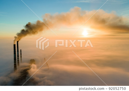 Aerial view of coal power plant high pipes with black smoke moving up polluting atmosphere at sunset. Aerial view of coal power plant high pipes with black smoke moving up polluting atmosphere at sunset. 92052750