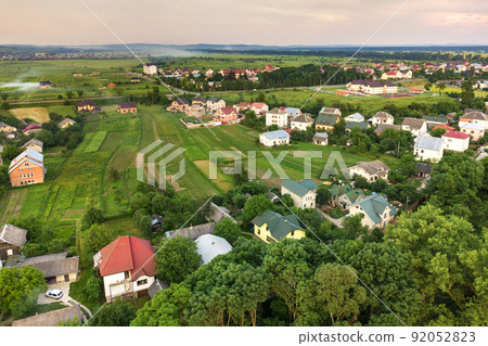 Aerial landscape of small town or village with rows of residential homes and green trees. 92052823