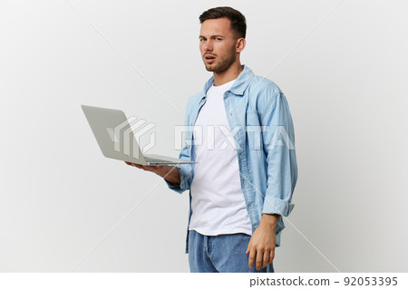 Confused irritated tanned handsome man in casual basic t-shirt shocked by gadget laptop breakdown posing isolated on white studio background. Copy space Banner Mockup. Electronics repair IT concept 92053395