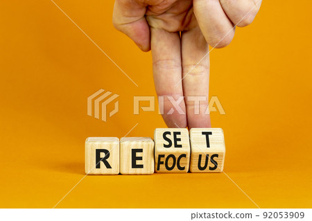 Refocus and reset symbol. Businessman turns cubes and changes the word 'refocus' to 'reset'. Beautiful orange table, orange background. Business refocus and reset concept. Copy space. Refocus and reset symbol. Businessman turns cubes and changes the word 'refocus' to 'reset'. Beautiful orange table, orange background. Business refocus and reset concept. Copy space. 92053909