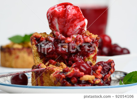 Cherry crumble pie decorated with a scoop of ice cream and drizzled with cherry sauce Cherry crumble pie decorated with a scoop of ice cream and drizzled with cherry sauce 92054106