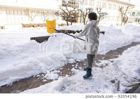 大雪過後的早晨,一名婦女在購物區鏟雪 大雪過後的早晨,一名婦女在購物區鏟雪 92054196