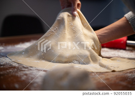 Stretching and pulling homemade vegan pastry dough for strudel Stretching and pulling homemade vegan pastry dough for strudel 92055035
