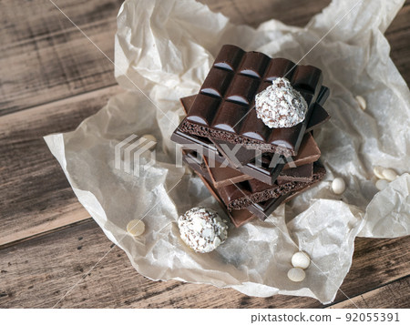 Chocolate bars tower and truffles on wooden surface. Sweet and delicious food concept Chocolate bars tower and truffles on wooden surface. Sweet and delicious food concept 92055391
