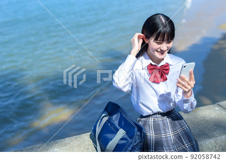 高中女生應用 SNS 海邊沙灘 instagram,坐落在美麗的海邊防波堤上,使用智能手機 高中女生應用 SNS 海邊沙灘 instagram,坐落在美麗的海邊防波堤上,使用智能手機 92058742