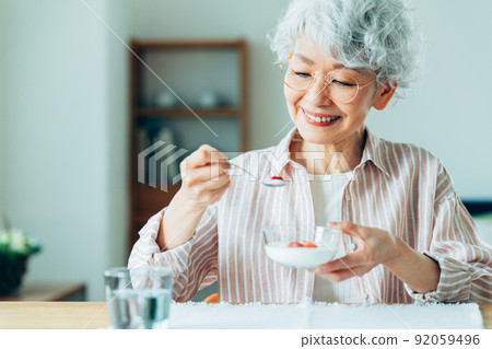Senior woman eating yogurt Senior woman eating yogurt 92059496