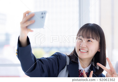 High school girls taking selfies on their smartphones High school girls taking selfies on their smartphones 92061302
