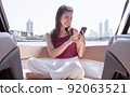 Woman sitting on boat and using mobile phone while travelling 92063521