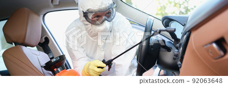 Hazmat female worker cleanse car interior with spray disinfectan 92063648