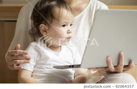 Half boy looking at a PC with his mother 92064357