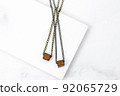 A pair of wooden cube necklaces on a marble stone 92065729