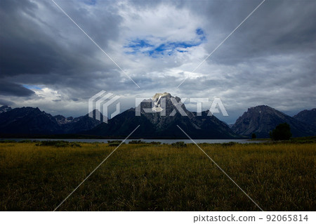 Grand Teton Mount Moran seen from Elk Island. Rocky mountains and lakes / grasslands with residual snow under the clouds. 92065814