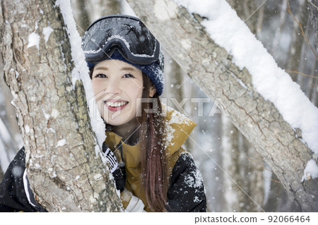 Snowboard girls coming out of the trunk of a tree Snowboard girls coming out of the trunk of a tree 92066464