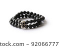 Bracelet made of natural black stones and skeleton charms on a white background 92066777