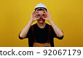 Funny smiling electrician in hardhat holds insulating tape in his hands. Electrician posing on yellow background 92067179