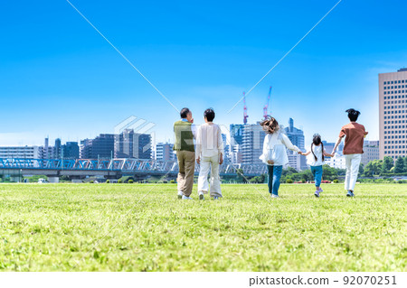 Three generations of families walking hand in hand in the park, back view Three generations of families walking hand in hand in the park, back view 92070251