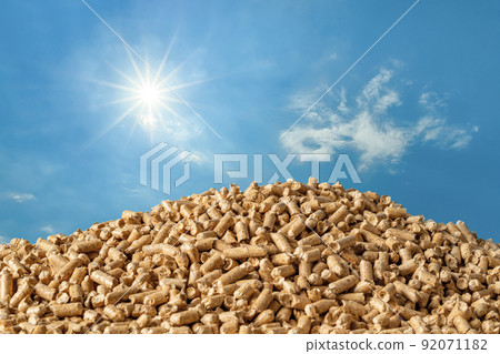 Heap of wood pellets against blue sky. Compressed sawdust granules. Heap of wood pellets against blue sky. Compressed sawdust granules. 92071182