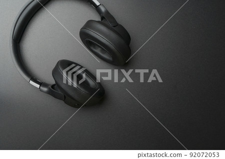 Headphones on a black background. Stylish studio headphones for listening to music, sounds, radio and podcasts lie on an empty dark table. 92072053