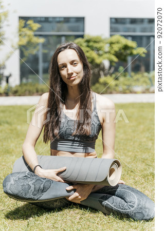 Girl with yoga mat before starting workout practice outdoors. Sport, healthy lifestyle, yoga meditation concept. 92072070