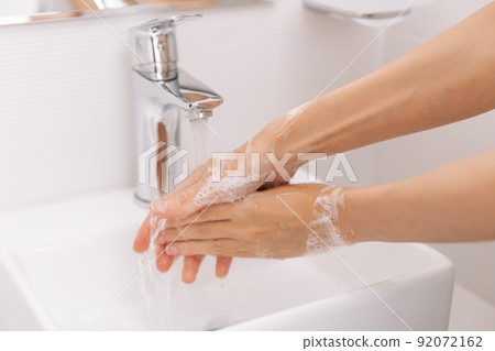 Washing hands under the flowing water tap. Hygiene concept hand detail. Washing hands rubbing with soap for corona virus prevention, hygiene to stop spreading corona virus in or public wash room. 92072162
