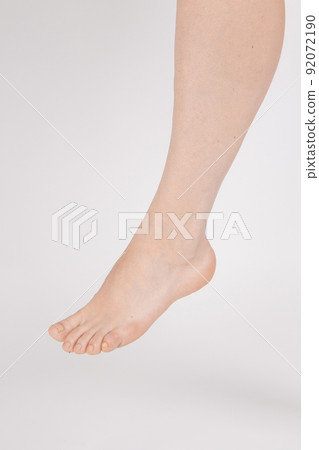 Barefoot and legs isolated on white background. Closeup shot of healthy beautiful female feet. Health and beauty concept. Side view of human foot ream with neutral manicure or pedicure. Sole of foot. 92072190