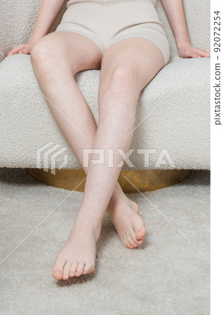 Long woman legs with smooth soft skin on sofa, couch or bed. A woman sits in a cozy home or apartment closeup. Woman doing skin care in the room. Beautiful sensual bare legs of a young woman. Long woman legs with smooth soft skin on sofa, couch or bed. A woman sits in a cozy home or apartment closeup. Woman doing skin care in the room. Beautiful sensual bare legs of a young woman. 92072254