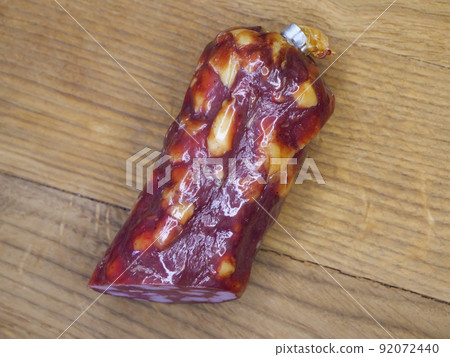 Half of an appetizing sausage on a wooden background, close-up shot. Food on a cutting board. Smoked sausage on a wooden rustic table 92072440