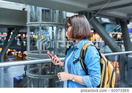 Middle-aged woman with a backpack in modern station building Middle-aged woman with a backpack in modern station building 92073869