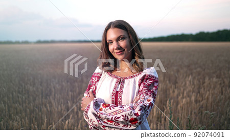 Smiling ukrainian woman in yellow ripe wheat field. Young lady in traditional embroidery vyshyvanka Smiling ukrainian woman in yellow ripe wheat field. Young lady in traditional embroidery vyshyvanka 92074091