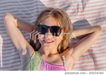 Portrait of a happy child on a beach towel with glasses. 92074169