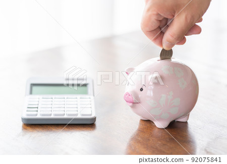 A man who puts a 100-yen coin in a piggy bank 92075841