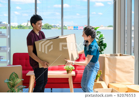 young asian couple smiling and enjoy when they carrying big cardboard box while relocation into new home on moving day, celebrating moving to new home concept young asian couple smiling and enjoy when they carrying big cardboard box while relocation into new home on moving day, celebrating moving to new home concept 92076553