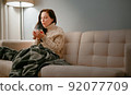 Woman sick with flu with a cup of hot cough tea blowing on him. 92077709