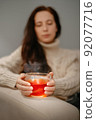A woman warms her hands on mug of tea after a walk. 92077716