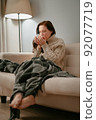 Woman sick with the flu virus while sitting is treated with hot tea. 92077719