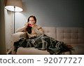 Woman caught a cold and drinks hot tea at home. 92077727