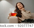 Woman sitting at home on the sofa unhealthy with a cup of hot tea. 92077747
