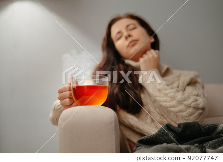 Woman sitting at home on the sofa unhealthy with a cup of hot tea. 92077747