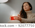 W oman holds a large mug of herbal tea for colds to treat a disease. 92077750