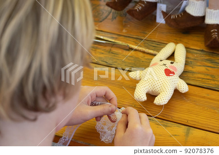 The child made a soft toy - a hare. The girl straightens her skirt on a toy. Easter Bunny. Handmade. Handmade soft toy The child made a soft toy - a hare. The girl straightens her skirt on a toy. Easter Bunny. Handmade. Handmade soft toy 92078376