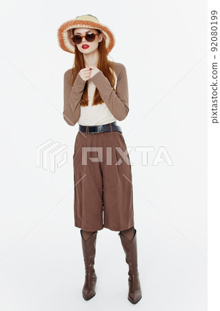 A full-length shot of a fashionable lady in a hat and glasses posing in motion on a white background in the studio. Cool banner for designers 92080199