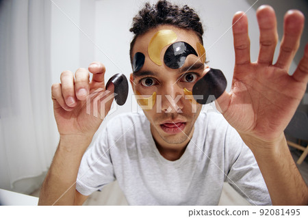 guy with curly hair many patches on the face touches face with hands light background 92081495