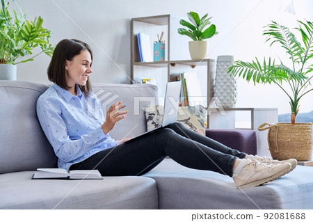 Young woman talking online using laptop for video call sitting on sofa at home Young woman talking online using laptop for video call sitting on sofa at home 92081688