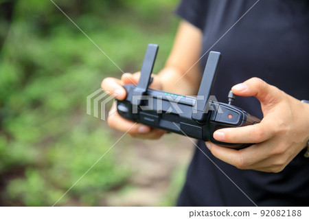 People remote control a flying drone in summer forest People remote control a flying drone in summer forest 92082188