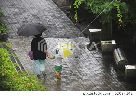 父母和孩子在雨天打著傘出去，和媽媽聊天時玩得開心 92084142